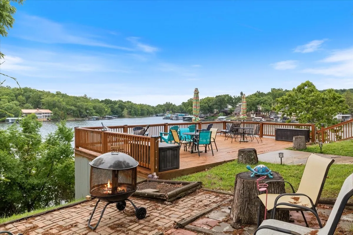 Outdoor deck area with ample seating and a fire pit, all oriented toward a stunning lake view. The setting is casual, ideal for gatherings, barbecues, or sipping drinks while enjoying the sunset.