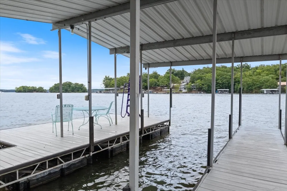 A peaceful lakeside dock featuring inviting green chairs positioned over calm water, framed by the natural beauty of the shoreline. The scene evokes relaxation and the anticipation of enjoying the lake from sunrise to sunset.