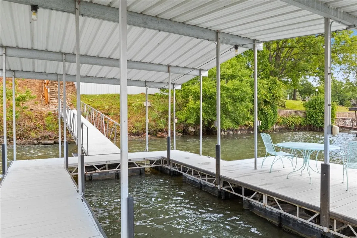 A peaceful lakeside dock featuring a table and chairs, with a pathway leading from the shore. The dock is surrounded by clear water and a tranquil natural setting, ideal for outdoor relaxation and activities.