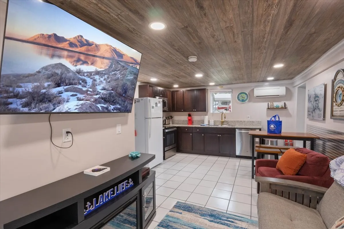 A cozy corner of the home with a television displaying a scenic mountain landscape, modern kitchen cabinetry, and a comfortable seating area. The atmosphere is warm and functional, suitable for family relaxation and reinforcing the sense of safety and convenience.
