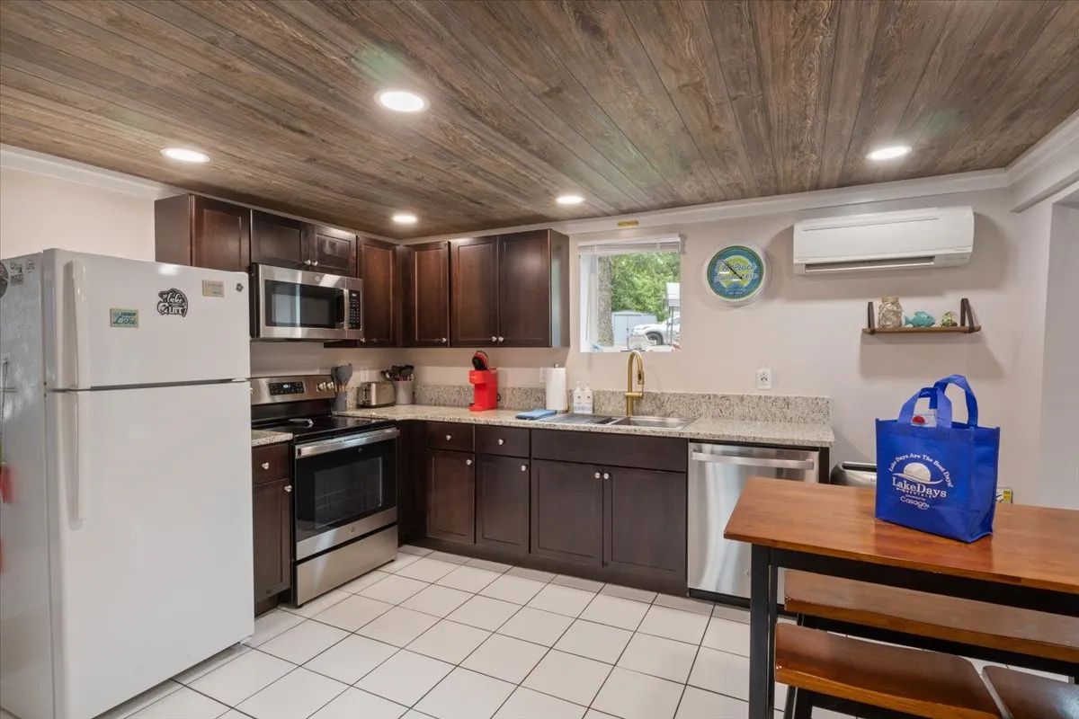 A warm, functional kitchen with stainless steel appliances, granite countertops, a wooden ceiling, and a central island. The setup is both practical and inviting, evoking the experience of preparing meals together.